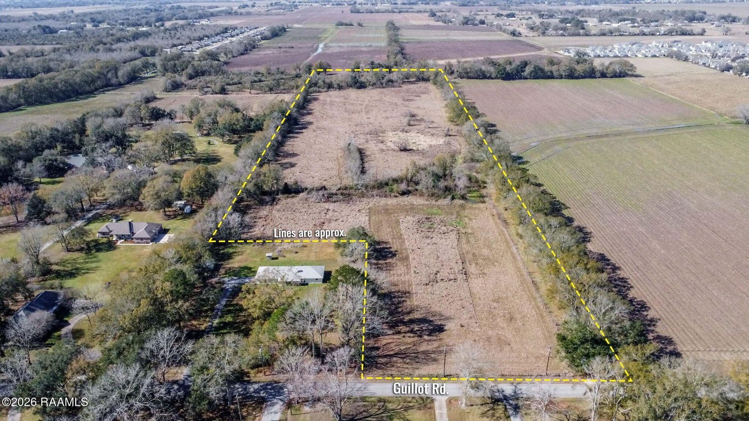 Aerial property view with yellow boundary lines marking cleared land among agricultural fields, trees, and nearby structures along Guillot Road.
